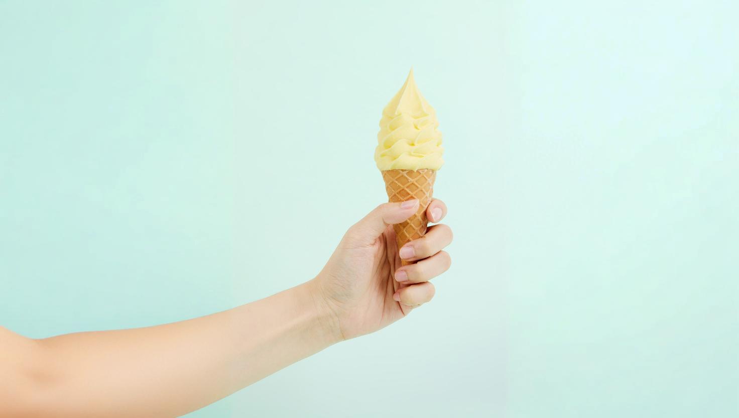 mão feminina segurando casquinha de sorvete de creme